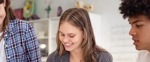 A group of smiling students working on a paper together