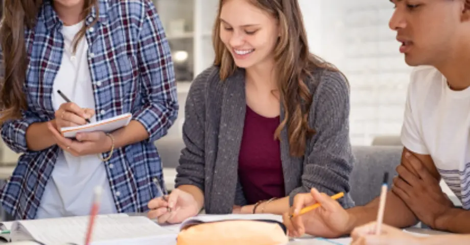 A group of smiling students working on a paper together