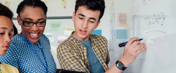 Student working at a whiteboard and reviewing information on a tablet device